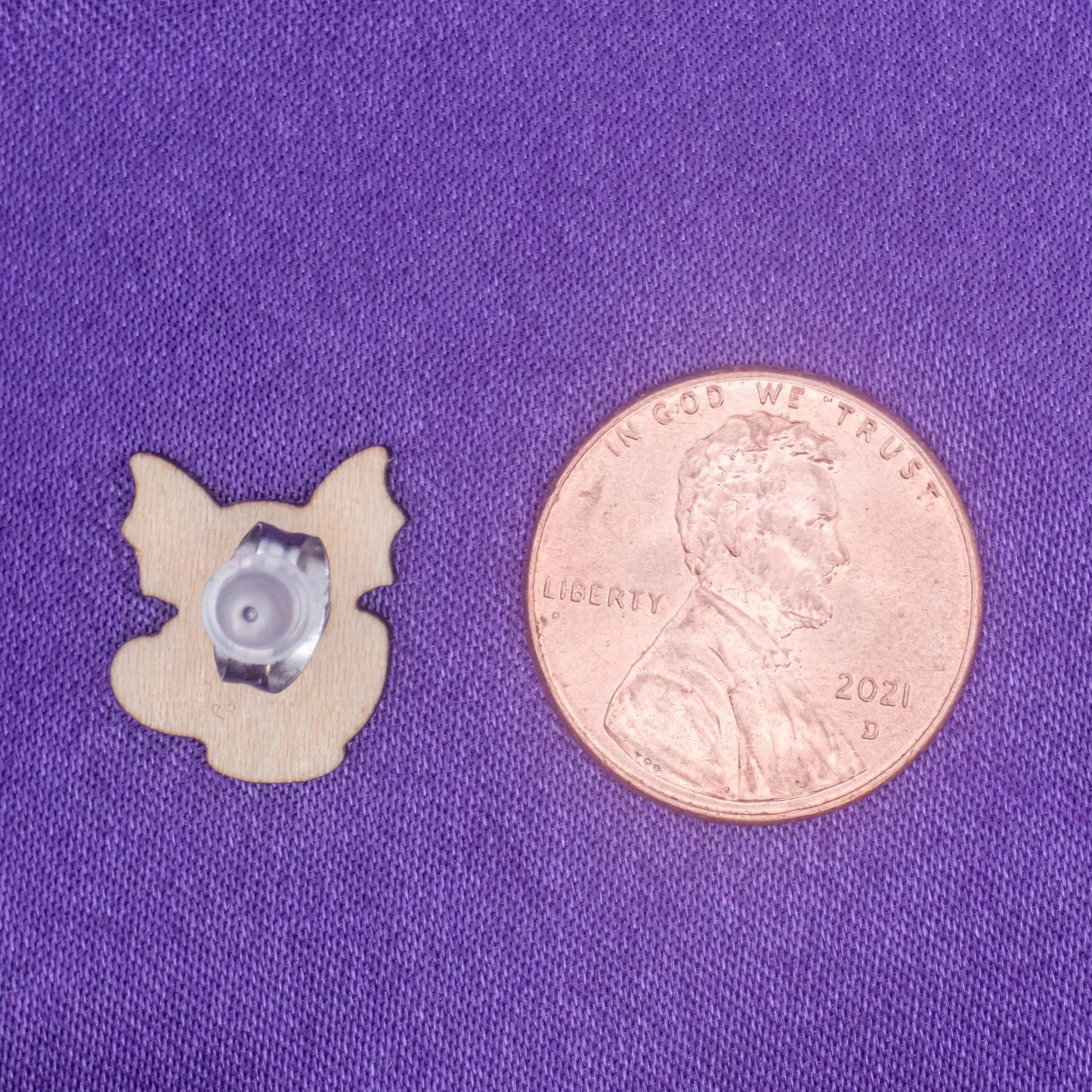 backside view of laser engraved earring beside a penny for scale