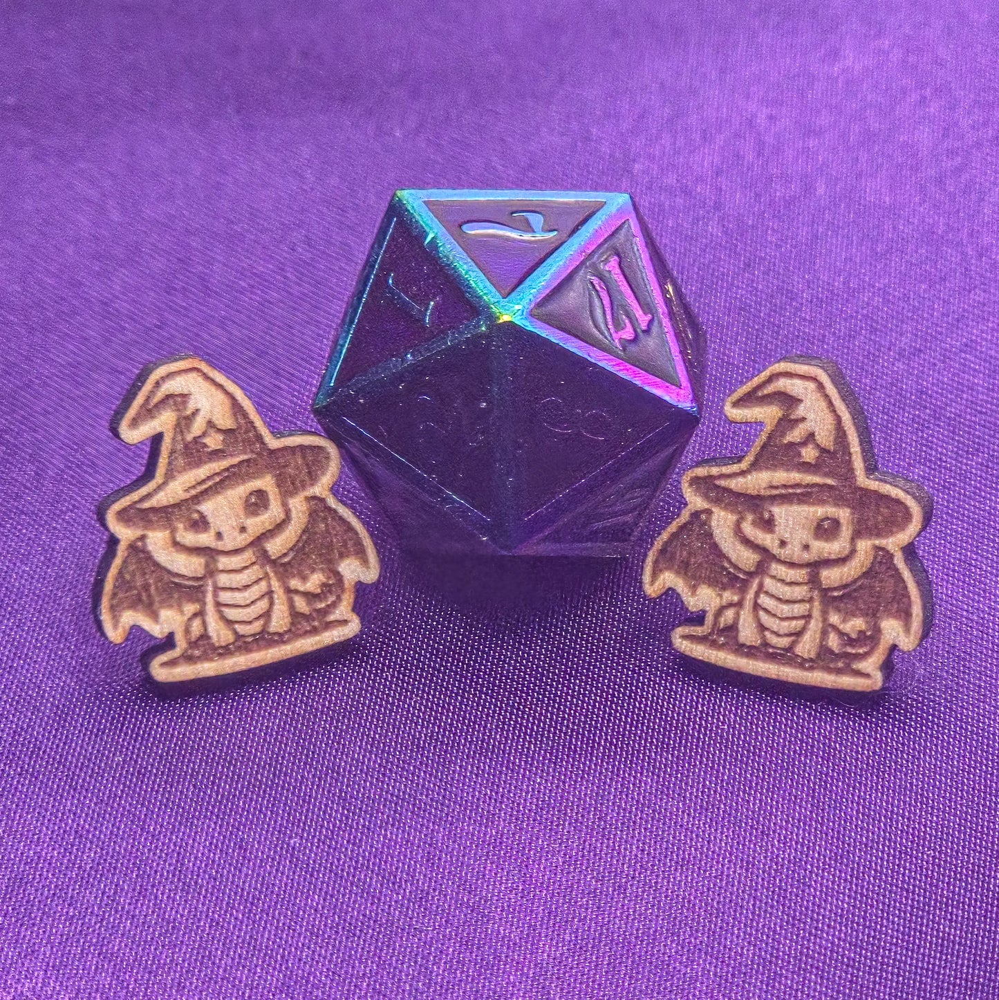 set of laser engraved earrings featuring dragons wearing wizard hats in front of a d20