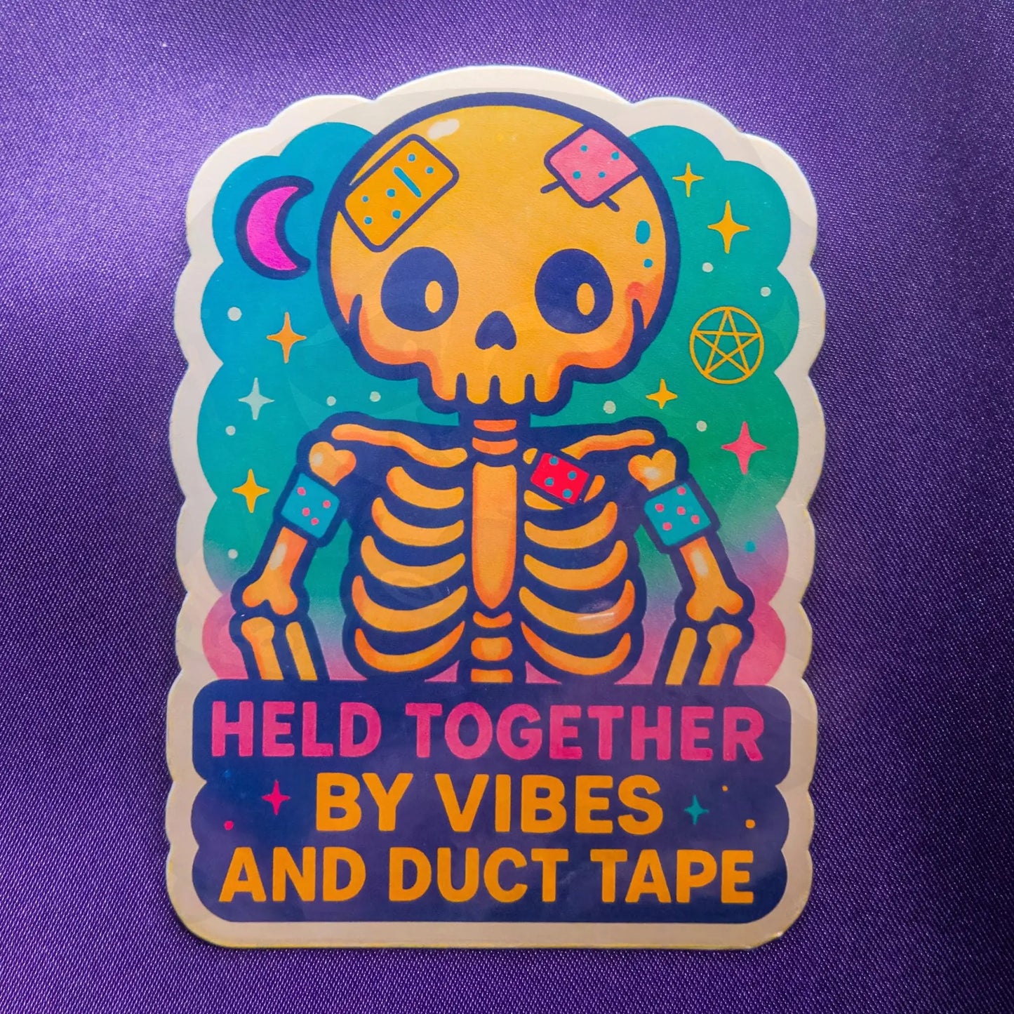 Colorful skeleton sticker with text 'Held Together by Vibes and Duct Tape' on a purple background