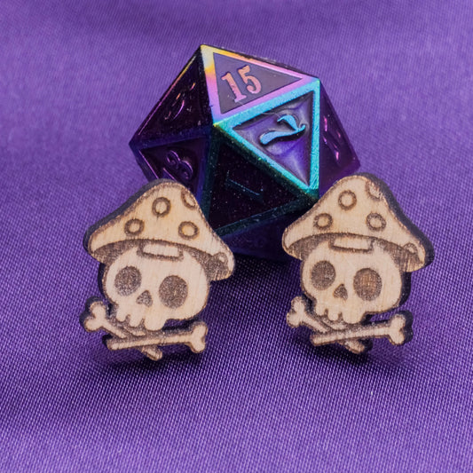 Two skull and mushroom earrings with a purple and blue die on a purple background