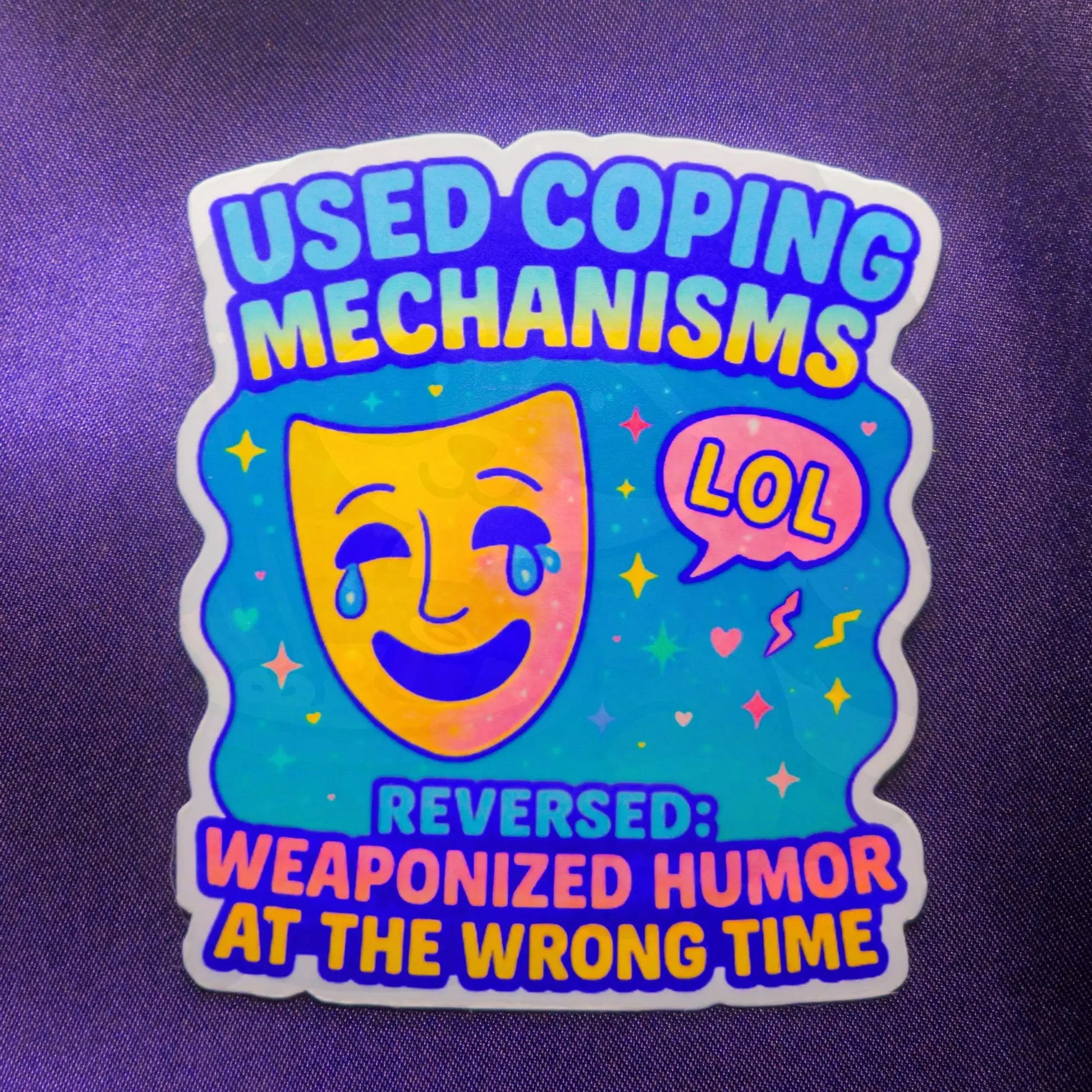 Sticker with a smiling theater mask and tears, captioned “USED COPING MECHANISMS” and “REVERSED: WEAPONIZED HUMOR AT THE WRONG TIME," on a purple background.